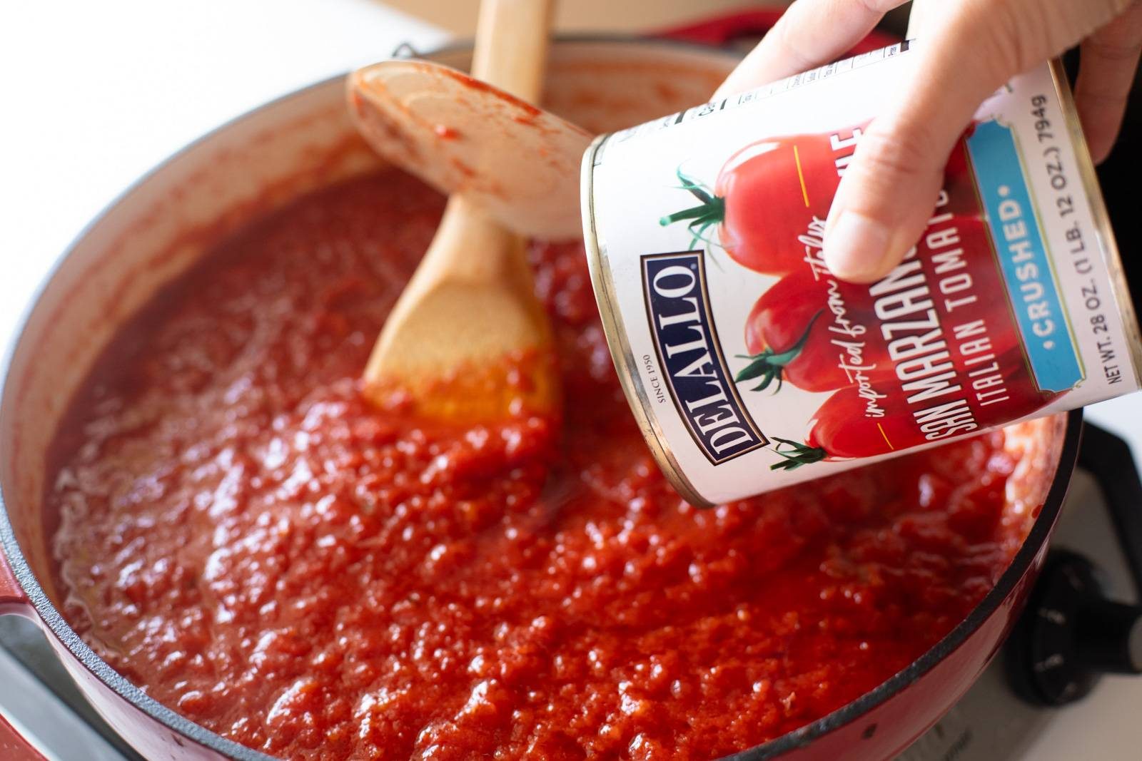 Pouring crushed tomatoes into a skillet.