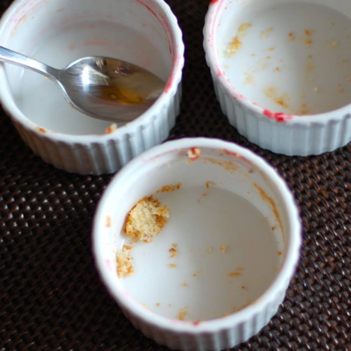 Empty white dishes with food remains and a spoon.