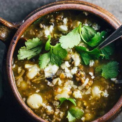 Mushroom Poblano Posole Verde in bowls with a spoon.