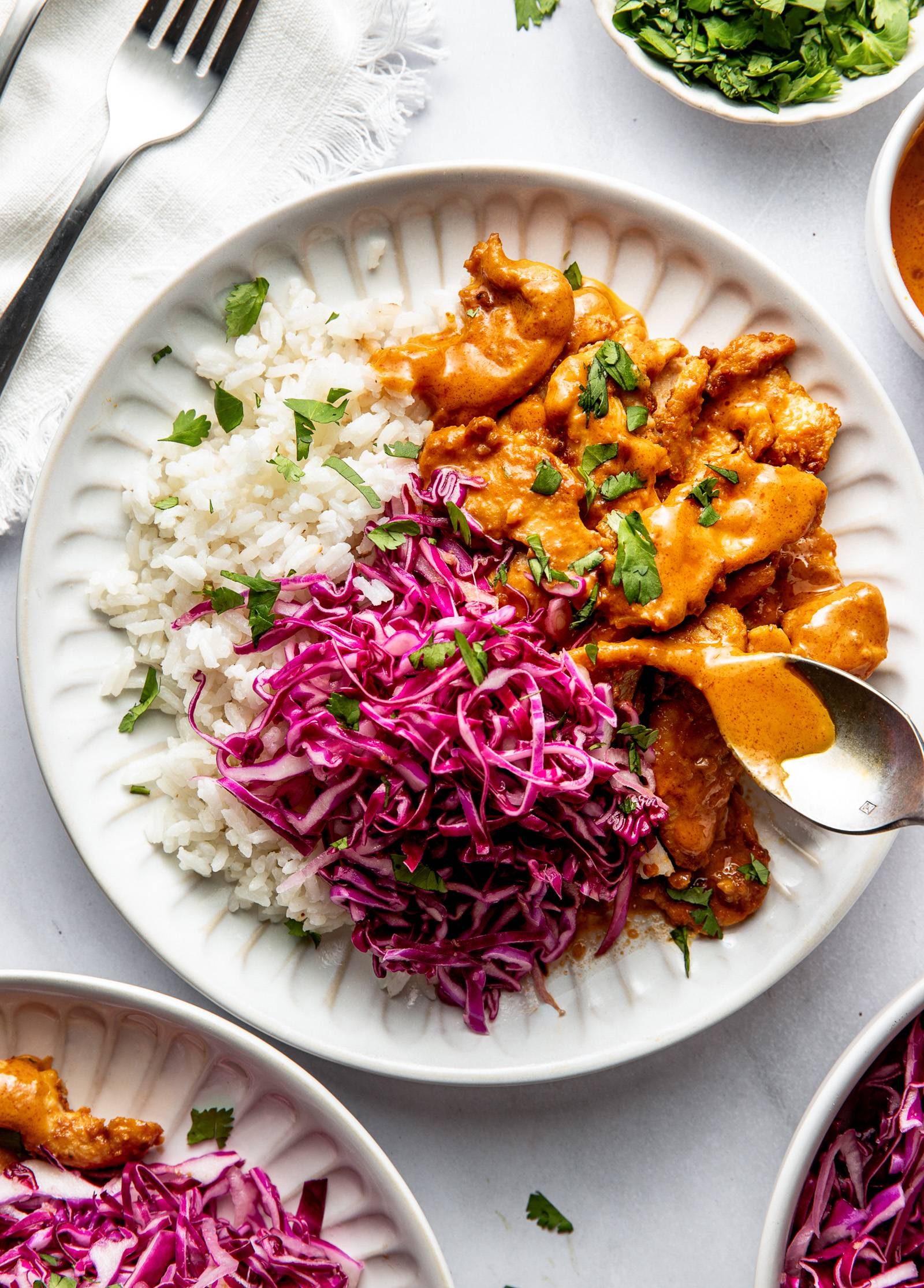 Peanut chicken on a plate with rice and slaw.